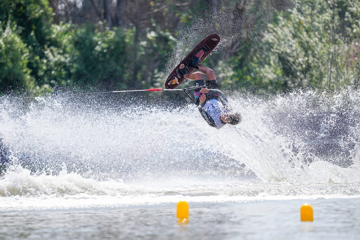 Water ski goes upside down in the air through the wake of the boat