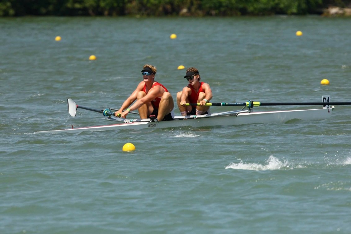 Two youth rowers compete on water.