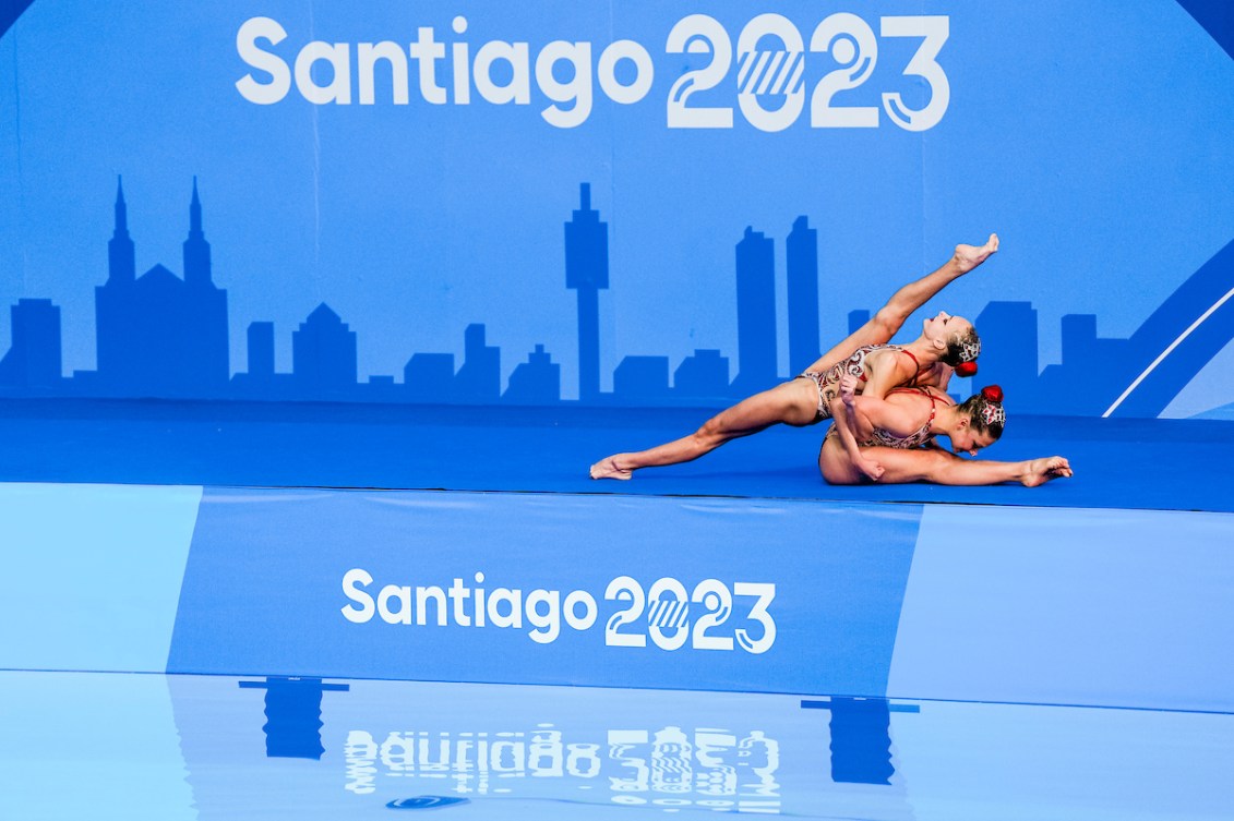 Two artistic swimmers pose on deck before the beginning of their routine.