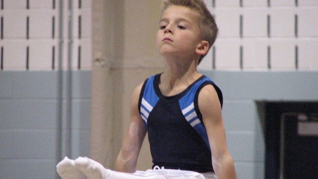 A young Felix Dolci is helped performing a gymnastics move