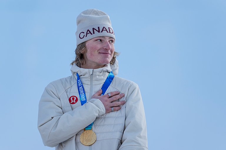 Canadian Eli Bouchard holds his hand over his heart while wearing a gold medal