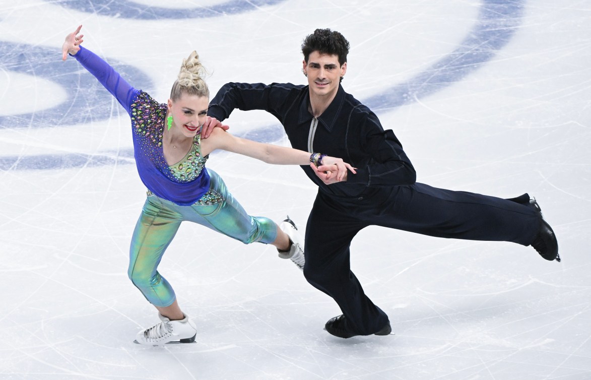 Piper Gilles in a green and purple outfit and Paul Poirier in a black outfit skate side by side