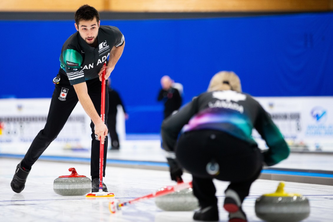 Colton Lott sweeps a red stone towards the house where his partner is back on to the camera 