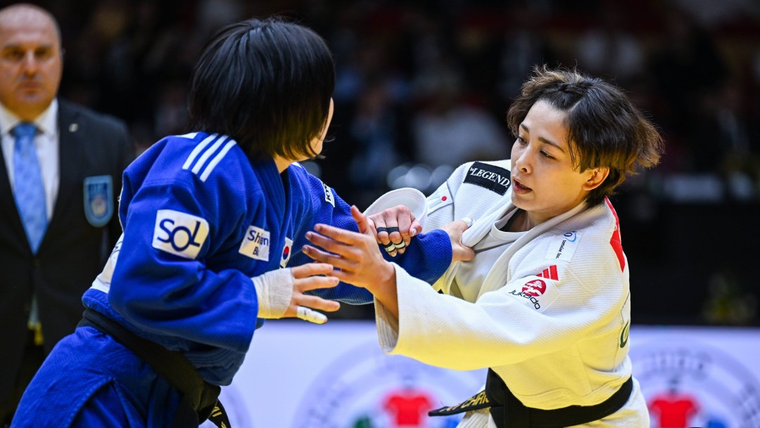 Two judokas grapple with each other, one is wearing white, one is wearing blue