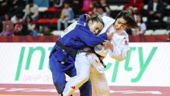 Kelly Deguchi in white fights another judoka in blue, trying to trip her up