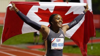 Mariam Abdul-Rashid holds the Canadian flag up behind her head while she smiles big