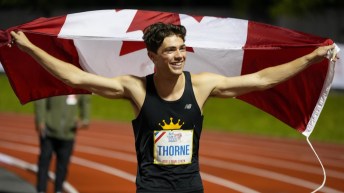 Craig Thorne in a black singlet holds the Canadian flag up behind his back