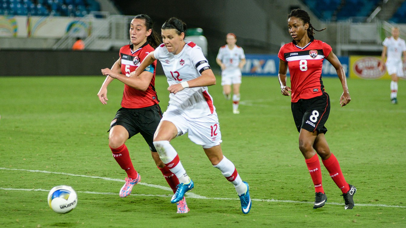 Christine Sinclair (centre, en blanc) contre Trinité-et-Tobago le 13 décembre 2015 au tournoi international Invitation de Natal (Photo: Vlademir Alexandre/Allsports). 