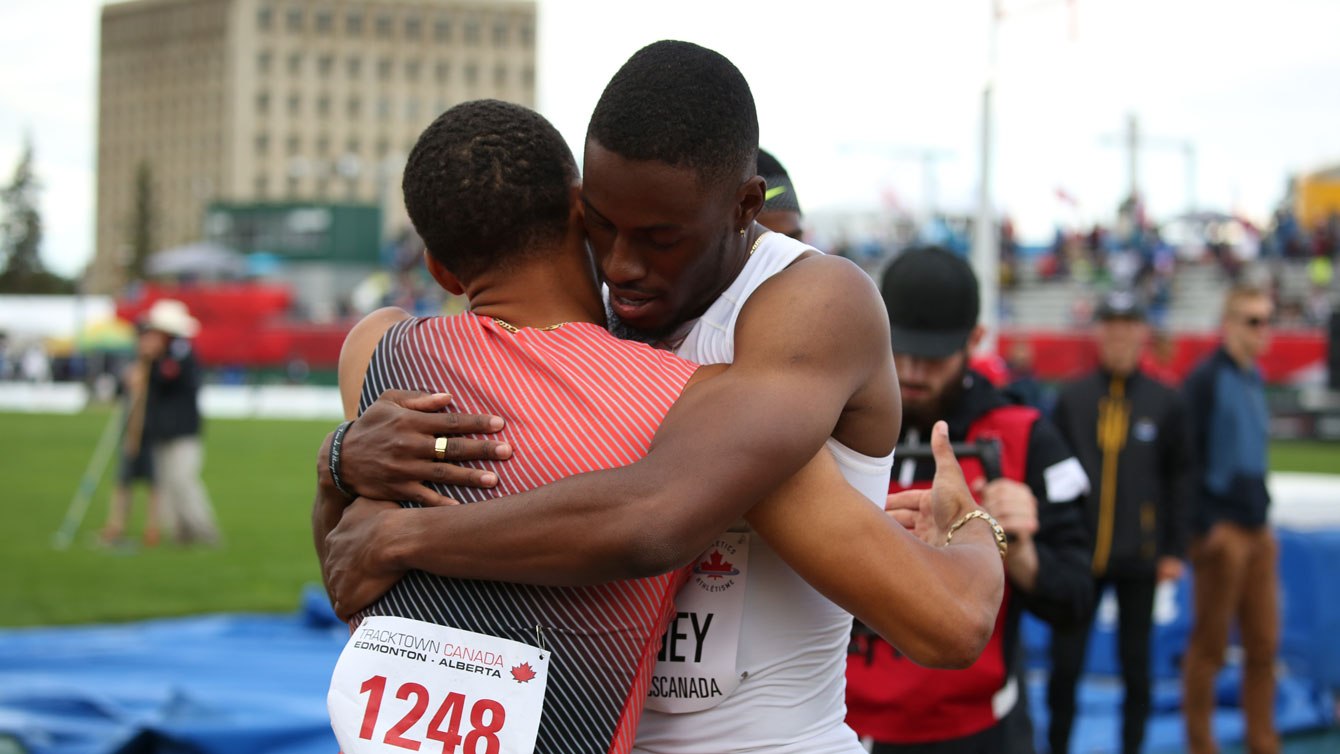 Accolade entre Andre De Grasse (en orange) et Brendon Rodney après la finale du 200 m aux Essais olympiques d'Athlétisme Canada, le 10 juillet 2016.