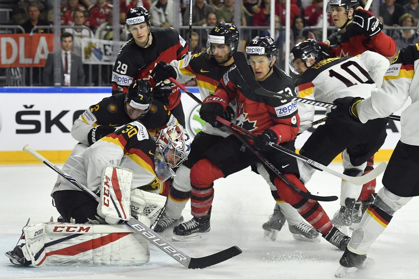 Le gardien allemand Philipp Grubauer (gauche) effectue l'arrêt face à Jeff Skinner du Canada (centre) au Championnat du monde de hockey 2017 à Cologne, en Allemagne, le 18 mai 2017. (AP Photo/Martin Meissner)