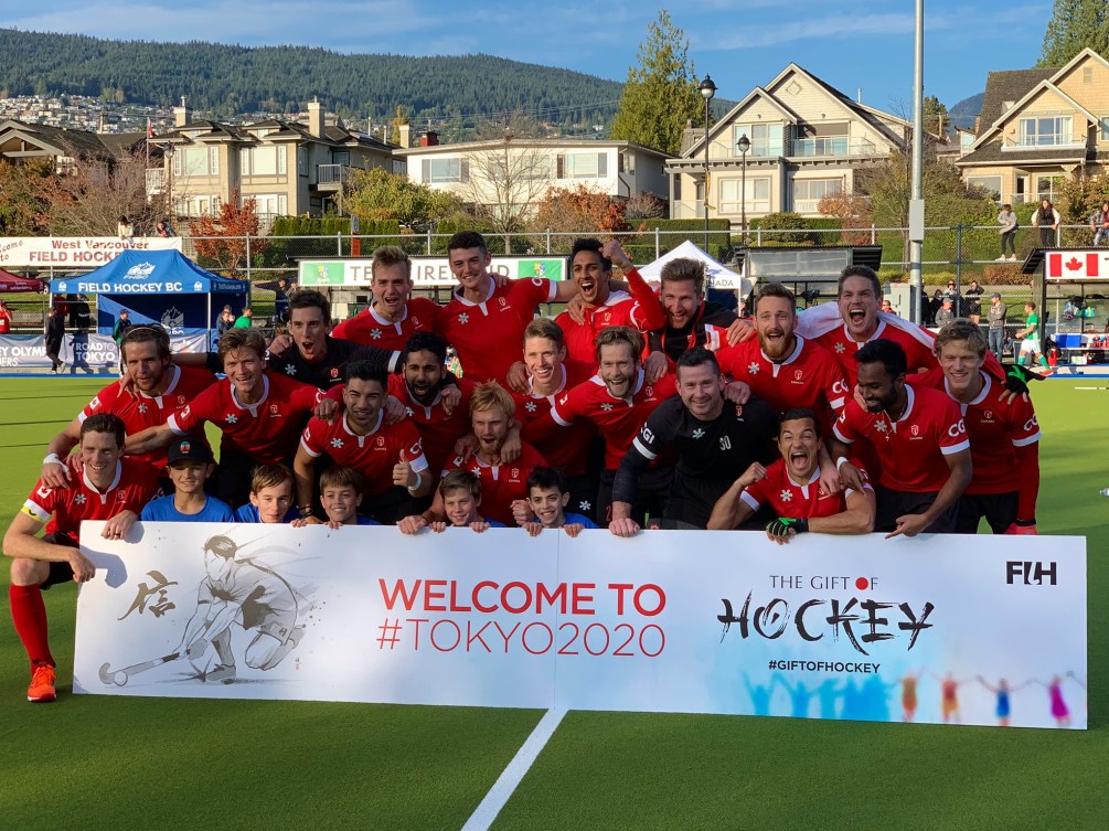 L'équipe de hockey sur gazon pose avec la banderole de qualification olympique