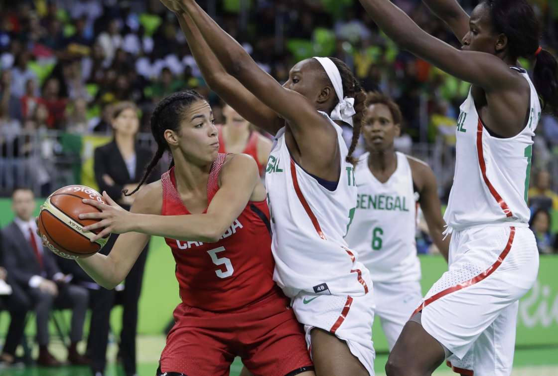 Une joueuse de basketball essaie de contourner deux joueuses adverses